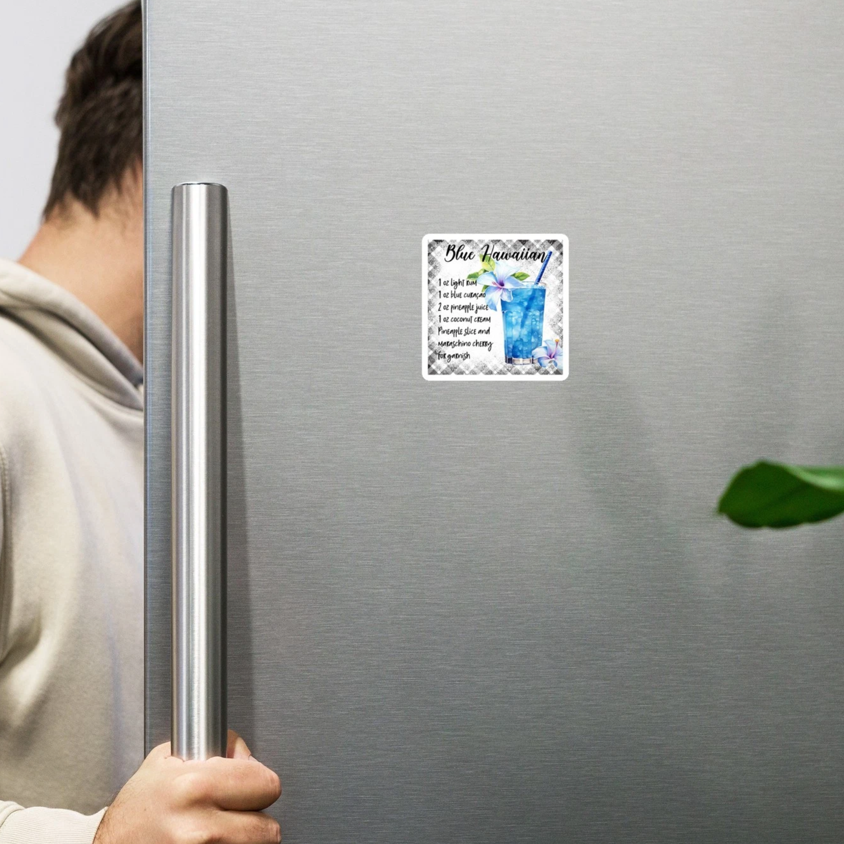 Person opening a refrigerator with a Blue Lagoon-themed magnet on the door.